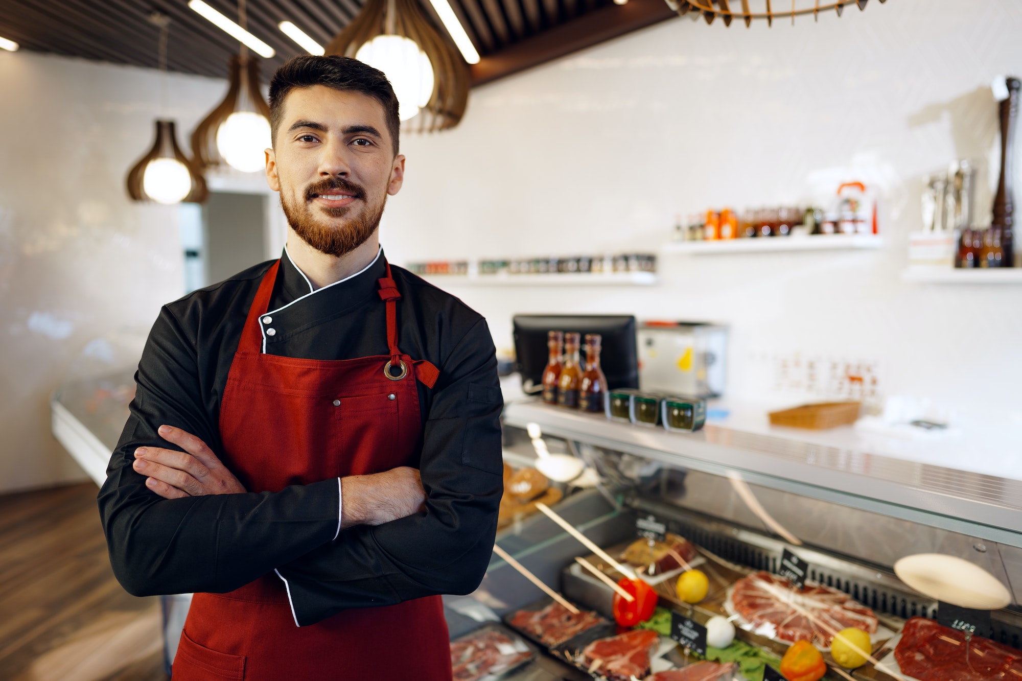 Portrait of a young man shopkeeper standing by meat stall in supermarket